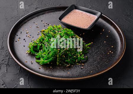 Wakame seaweed salad with sesame seeds on black plate Stock Photo