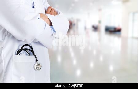 Cropped shot of an unrecognizable male doctor standing with his arms folded inside of a hospital during the day and copy space Stock Photo