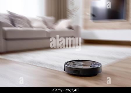 Robotic vacuum cleaner on the floor in cozy modern living room with motion blur effect Stock Photo