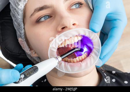 Closeup view of dentist using dental curing UV lamp on teeth of patient Stock Photo