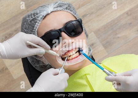 Patient with cheek retractor lying in dentist office Stock Photo
