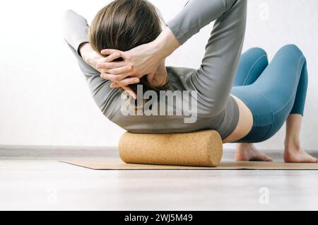 Woman doing back muscles self massage on cork roller Stock Photo
