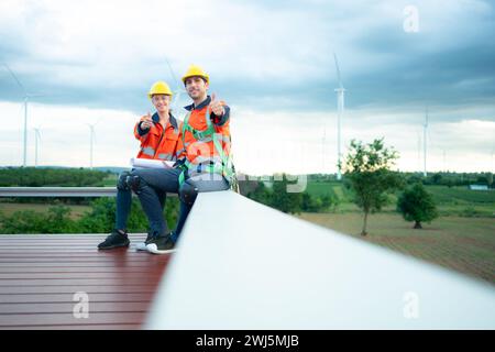 Two engineers discussing a project of wind turbine, They are sitting on a wooden platform, The concept of natural energy from wi Stock Photo
