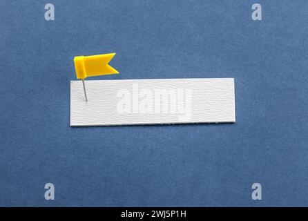 White paper pinned with a pushpin on a blue background with copy space. Business branding Stock Photo