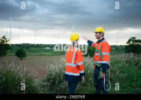 Two engineers shaking hands on the background of wind turbines in the field Stock Photo