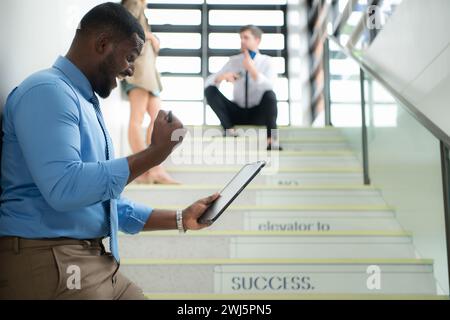 Portrait of businessman using digital tablet while standing on stairs in office building Stock Photo