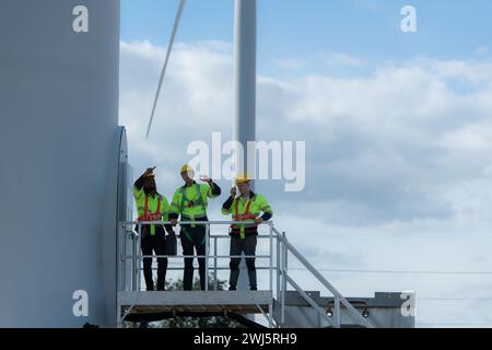 Group of engineers and technicians standing on the stairs of a wind turbine, The concept of natural energy from wind. Stock Photo
