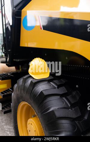 A yellow hard hat lies on the wheel of a construction machine. Stock Photo
