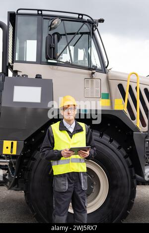 Engineer with tablet computer stands on the stairs to the cab of a truck.. Stock Photo