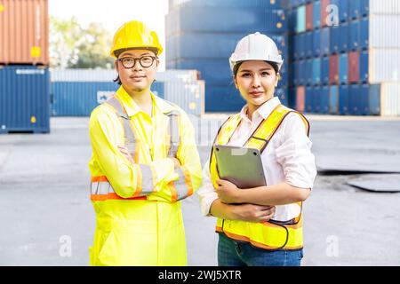The two Southeast Asian engineers posing confidently in front of shipping containers. Stock Photo