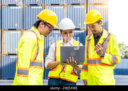 A female worker and two male workers wearing yellow safety vests using a laptop. Stock Photo