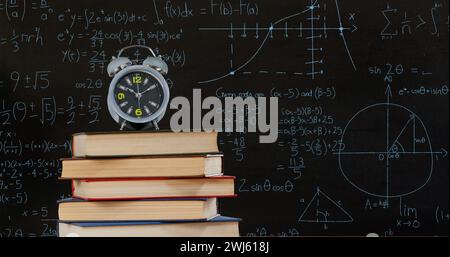 Silver clock on books with math equations in the dark background. Stock Photo