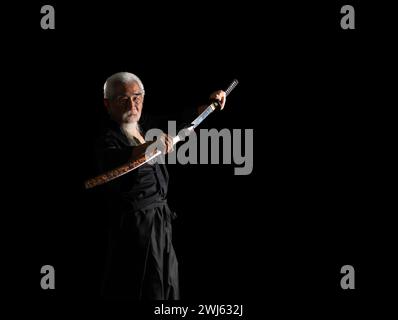 Senior Japanese samurai with katana sword on black background, studio shot Stock Photo