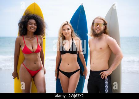 Group of friends in swimsuits posing with surfboards on the beach. Stock Photo