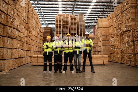 Portrait of a group of workers work in a woodworking factory, Standing with arms crossed in a wooden warehouse. Stock Photo