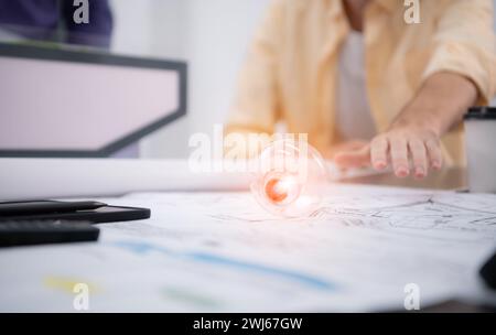 Young architect working on new project in his office He carries a light bulb that should not be used in buildings because it is Stock Photo
