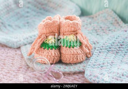 Peachy crocheted baby booties on knitted squares Stock Photo