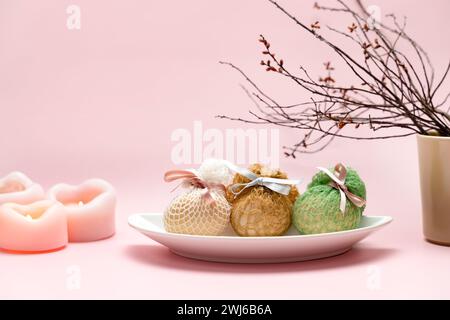 Eggs decorated artisanal nets and ribbons on white plate. Branch and candles simple pastel rustic background for traditional Easter holiday card Stock Photo