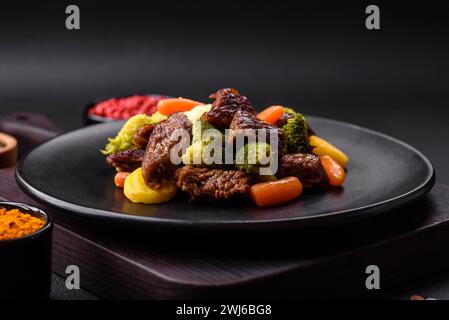 Delicious fresh beef and vegetables carrots, broccoli, cauliflower on a black plate Stock Photo