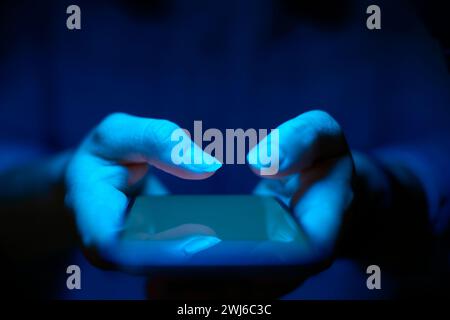 Close Up Of Woman Using Mobile Phone With Blue Lighting Effect Stock Photo