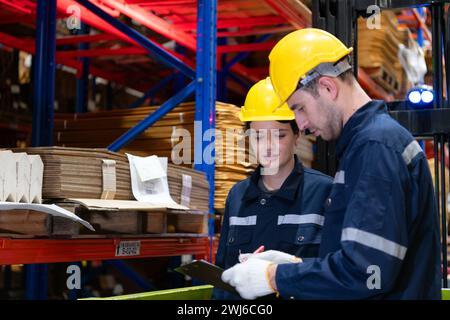 Both of warehouse staff working together in a large paper warehouse using a tablet computer Stock Photo