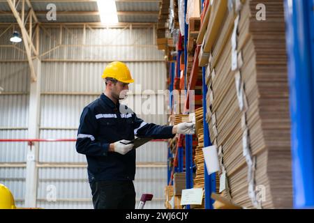 Young male warehouse worker checking stock in a warehouse. This is a large paper package storage and distribution warehouse. Stock Photo