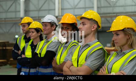 Group of diverse factory workers standing in a row and young female in center looking at camera Stock Photo