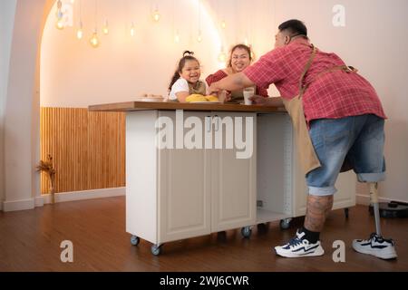 A plus-size family with a father wearing a prosthetic leg, Eat together after cooking and daughter drinks milk for health in the Stock Photo