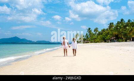 Koh Mook a young couple of caucasian men and Thai Asian woman walking at the beach in Thailand Stock Photo