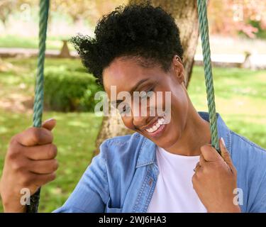 Smiling Mature Woman At Home Outdoors Sitting On Garden Swing Stock Photo