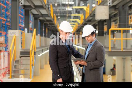 Two businessmen inspect the electric train system using a tablet to reserve equipment for use in repairing tracks and machinery Stock Photo