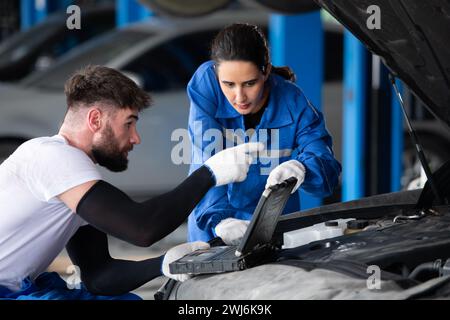 Professional auto mechanic man and woman working together in auto repair shop. Stock Photo