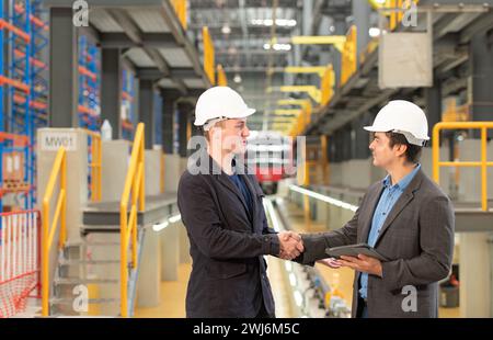 Two businessmen shaking hands after reaching an agreement to reserve equipment for use in repairing tracks and machinery of the Stock Photo