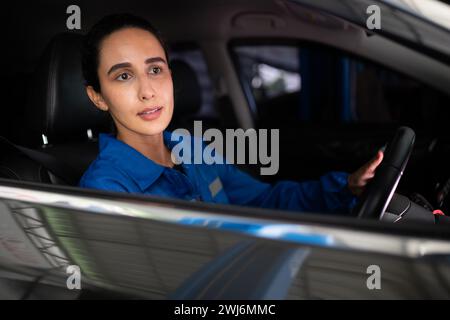 Portrait of female auto mechanic sitting behind steering wheel in a car Stock Photo