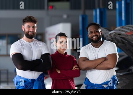 Portrait of two guy professional auto technician and a female customer standing in an auto repair shop with arms crossed Stock Photo