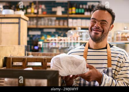 Smiling Man With Down Syndrome Stocking Shelf With Bread In Food Shop Stock Photo