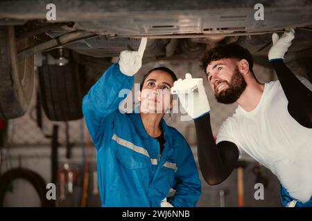 Bothe of car mechanic working in an auto repair shop, Check the operation of the engine of under the car that comes in for repai Stock Photo