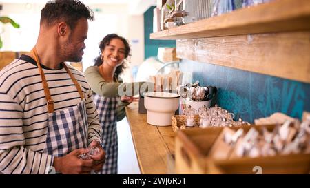 Woman And Man With Down Syndrome Working In Coffee Shop Or Restaurant Stock Photo