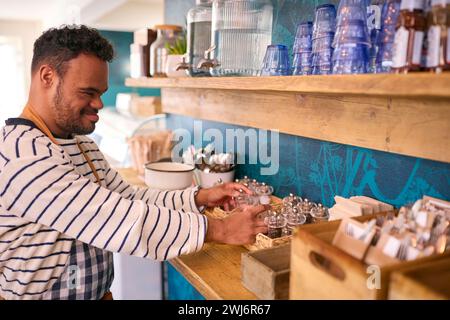 Man With Down Syndrome Working In Coffee Shop Or Restaurant Stock Photo