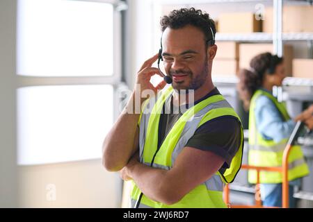 Man With Down Syndrome Working In Warehouse Wearing Headset Stock Photo