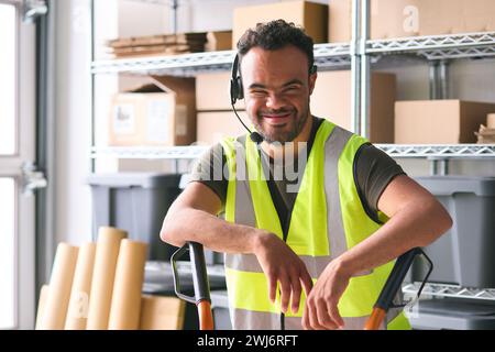 Portrait Of Man With Down Syndrome Working In Warehouse Wearing Headset Stock Photo