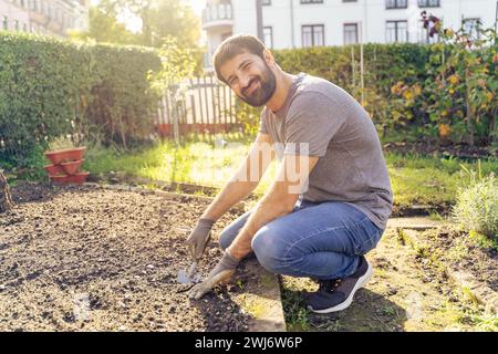 Young arabic smiling bearded farmer working in urban horticultural flower garden Stock Photo