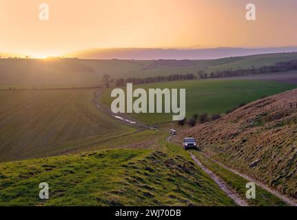 Land Rovers climbing on a byway to Sugar Hill on the Marlborough Downs at sunset. Wiltshire, England. Stock Photo