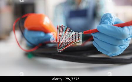 Hands with a voltmeter check colored wires in the cable, blurry Stock Photo