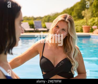 Two Mature Female Friends Wearing Swimsuits In Outdoor Pool On Spa Day Stock Photo