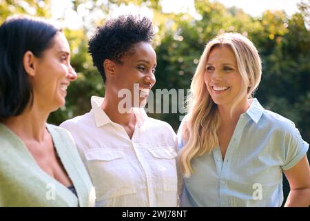 Three Smiling Mature Female Friends Outdoors Spending Time In Countryside Together Stock Photo