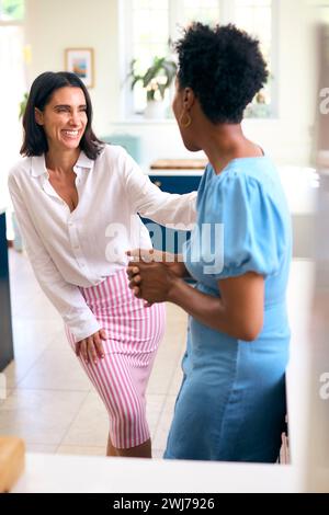 Two Mature Female Friends At Home Talking And Catching Up In Kitchen Together Stock Photo
