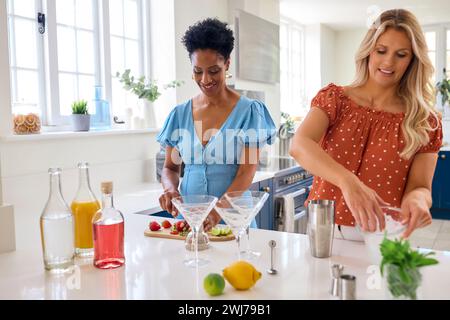 Two Mature Female Friends At Home Having Fun Mixing Cocktails Together Stock Photo