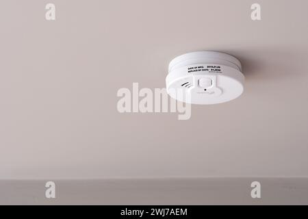 A Kidde 29HD optical smoke alarm installed on the ceiling of a room in a UK home. The battery powered fire alarm conforms to EN14604 Stock Photo