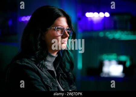 Close Up Of Female Computer Hacker Sitting In Front Of Screens Breaching Cyber Security Stock Photo